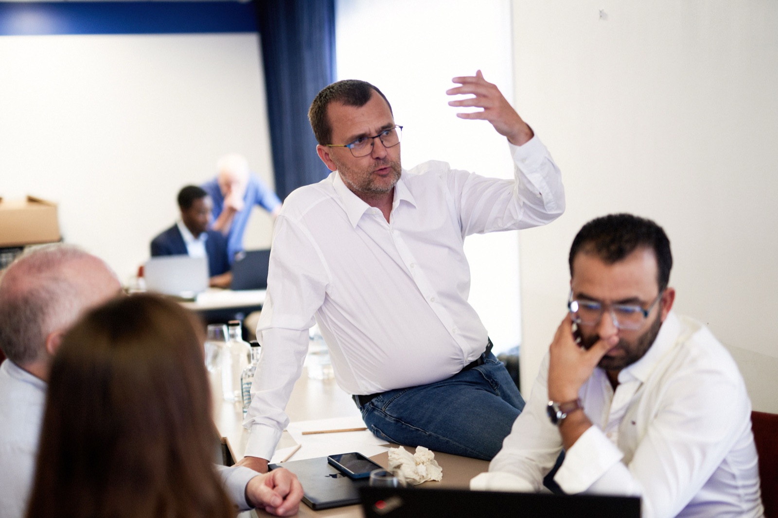 Trois consultants autour d&rsquo;une table de travail, en pleine discussion.